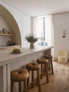 A modern residential kitchen featuring minimalist design with wooden stools and countertops.