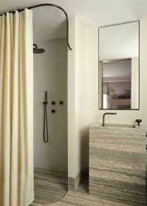 Modern bathroom with marble floor, sink, and shower area enclosed by a beige curtain.