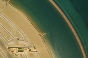 Aerial view of a modern beachfront property with concrete structures and sandy beach.