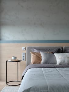 Modern minimalist bedroom with a gray headboard bed, wooden nightstand, and ceiling lighting