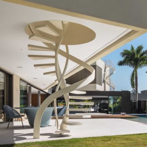 Modern residential house exterior featuring a metal spiral staircase and a palm tree