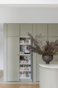 Minimalist green kitchen storage unit with pull-out drawers and shelves.