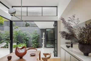 A modern dining room with wooden furniture, plants, and minimalist decor.