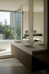 Modern minimalist bathroom featuring a white bathtub, wooden countertop with double sinks, and large glass windows overlookin