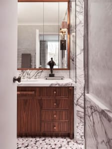 A modern bathroom featuring marble countertops, wooden cabinets, and patterned floor tiles.