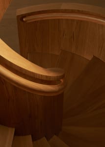 A modern, wooden spiral staircase with a polished finish.