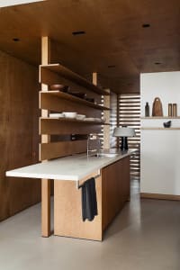 A modern kitchen featuring a minimalist white countertop and wooden furniture.