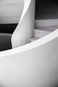 A modern minimalist staircase featuring concrete steps and a white wall.