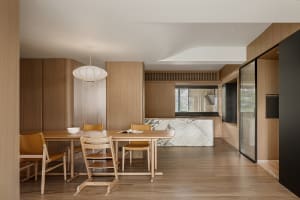 Modern, minimalist kitchen and dining area with wooden furniture and white marble countertops.