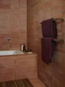 A bathroom shower area with terracotta tiles and wooden flooring.