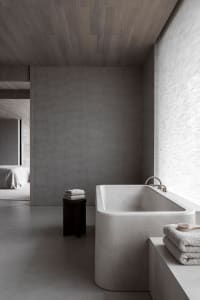 Minimalist bathroom featuring a concrete bathtub and wooden accents.