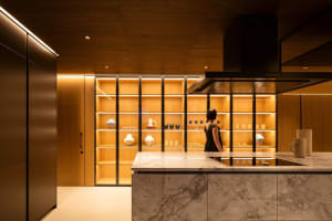 A modern residential kitchen with wooden shelves, white countertops, and black cabinets.