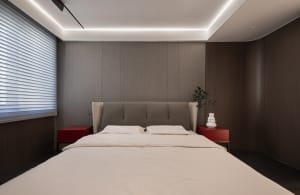A modern bedroom with a white bed and red side tables.