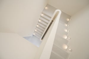 A modern staircase with illuminated glass treads and a cylindrical support column.