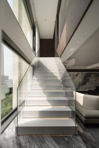 Modern staircase with glass railing and marble steps.