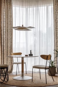 Modern dining room featuring minimalist design, wooden chairs, round table, and geometric curtains.