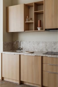 A modern kitchen featuring wooden cabinets, a sink, and a backsplash with a speckled pattern.