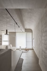A modern minimalist living room featuring a concrete floor, white furniture, and simple decor.