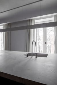 A minimalist kitchen with a concrete countertop and a modern sink.