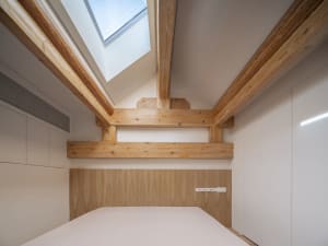 A modern bedroom with white lighting and wooden elements.