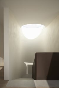 A modern stairwell with smooth concrete walls and a circular light fixture at the top.