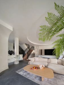 A modern living room with marble and concrete walls, a curved ceiling, a white sofa, and a wooden coffee table.