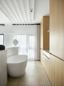 Modern bathroom featuring white walls, a freestanding bathtub, and wooden cabinets.