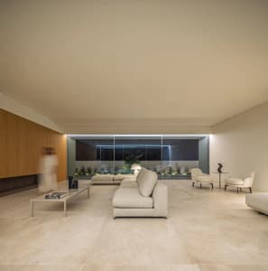 A modern living room with minimalist furniture, marble flooring, and a glass wall.