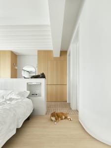 A modern minimalist bedroom with white walls, wooden furniture, and white tiles on the wall.