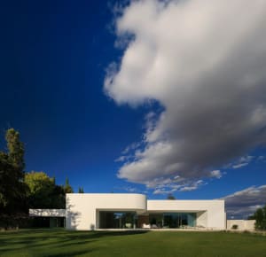 Modern residential exterior featuring large glass windows and a minimalist design.