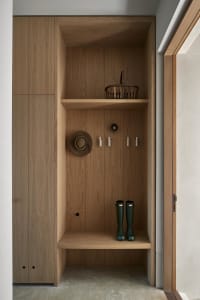 A modern entryway featuring wooden shelves, a basket, a cowboy hat, and green rain boots.