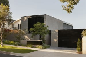 A modern house with a concrete exterior featuring large black windows.