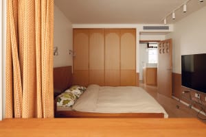 A modern minimalist bedroom with wooden furniture and a single bed