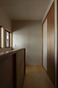 A modern corridor with wooden paneling and a minimalist design, featuring a light switch and a small window.