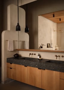 Modern minimalist bathroom featuring sleek concrete countertops, wooden cabinets, and black pendant lights.