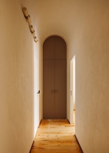 Hallway with a modern storage cupboard featuring concrete walls and wooden flooring.