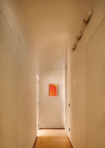 A minimalist hallway with smooth plaster walls and a wooden floor.