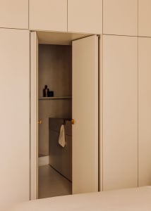 A minimalist living space with a hidden room revealed through a single door, featuring a concrete interior.
