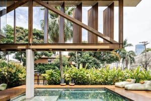 Modern residential outdoor area featuring concrete and wooden structures, surrounded by lush greenery.
