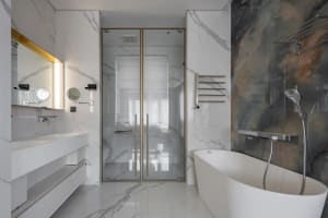 Modern bathroom with marble walls and floor, featuring a freestanding bathtub, a glass-enclosed shower, and a floating vanity