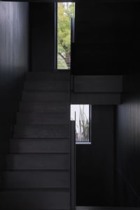 A modern black staircase with wooden steps in a dark interior space.