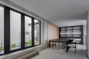 A modern dining room featuring wooden furniture and glass elements, with a minimalist design.