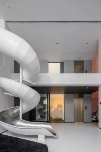 A modern interior space featuring a white metal slide and a concrete wall