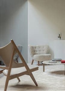 Modern living room featuring wooden furniture and sheepskin upholstery, with a round marble coffee table and a minimalist des