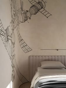 A minimalist bedroom with a smooth, fabric-textured bed and a large, intricate wall mural depicting a space station.