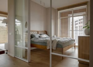 Modern minimalist bedroom featuring wooden furniture and light wooden flooring.