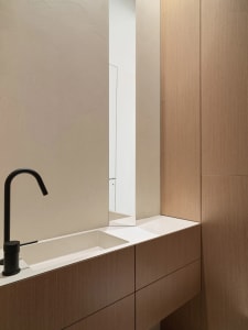 Modern bathroom with a black faucet and a long, rectangular wooden cabinet.