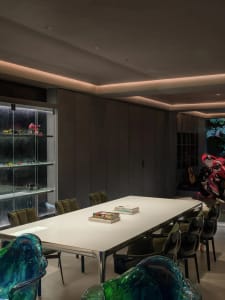 A modern office space with a large table and chairs, glass partition, and motorcycle display.