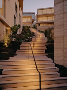 Modern residential stairs with concrete steps and railings on a hillside.