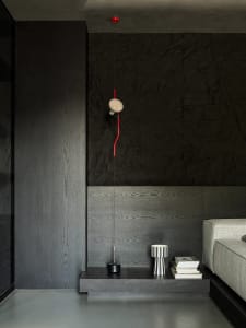 A minimalist living room featuring dark wood walls, concrete flooring, and a gray sofa.